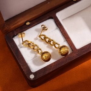 Long gold drop earrings with Cuban chain and solid ball pendant on a wooden jewelry box