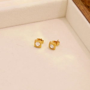 Makroaufnahme goldener quadratischer Ohrstecker mit Kristall in einer Samtbox