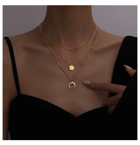 Close-up of gold layered necklace featuring sun and crescent moon pendants on model