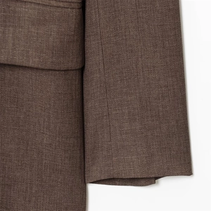 Gros plan détaillé du tissu texturé marron foncé et des coutures d'un blazer chic