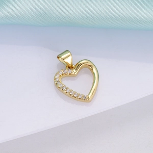 Detailed close-up of 18K gold heart pendant with inlaid crystals on white surface