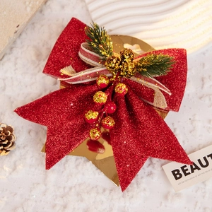 Detail of red glitter Christmas bow with mini pine cones and berries on snow background