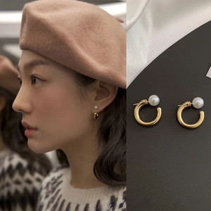 Elegant gold C-shaped pearl earrings shown on model and close-up detail display