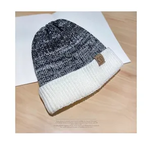 Detail of marl grey knit beanie with white ribbed cuff and brown leather CO. label