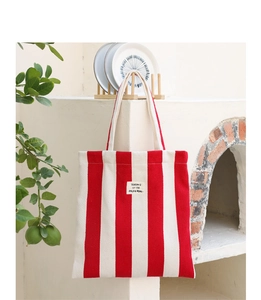 Detail of red and white striped canvas tote bag with SEASON 12 logo in a lifestyle setting