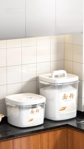 Detailed view of sealed flour storage canisters with handles on a marble countertop