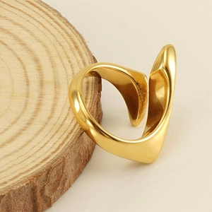 Dettaglio macro di un anello aperto dorato a forma di cuore irregolare su legno