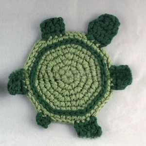 Macro detail of handmade crochet turtle coaster with intricate green cotton knitting