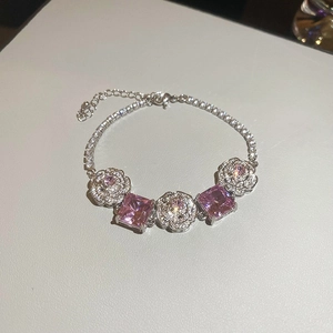 Close-up of luxury silver-toned bracelet with pink gemstones and zircon flower motifs