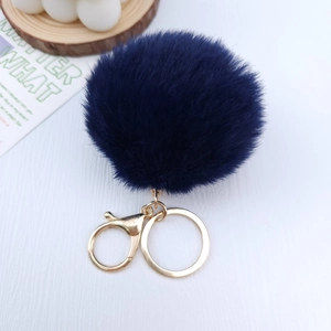 Close-up of deep blue plush pompom keychain with golden lobster clasp and metal ring