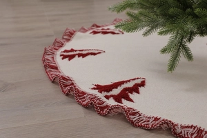 Detailed close-up of knitted Christmas tree skirt with red tassels and tree embroidery