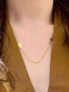 Gros plan d'un collier doré avec croix et médaille religieuse ovale sur modèle