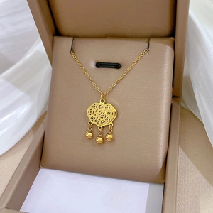 Minimalist gold titanium steel lock necklace with beads displayed on silk fabric