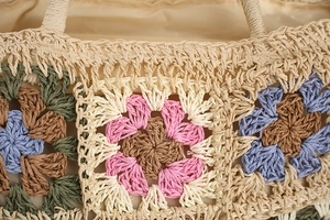 Detailed close-up of colorful crochet flower patches on a handmade woven straw beach bag