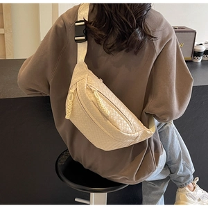 Detailed view of beige woven crossbody chest bag with adjustable wide strap and knot zipper