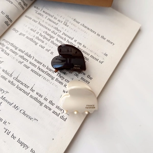 Nahaufnahme von herzförmigen Acetathairclips in Creme und Braun auf einem Buch