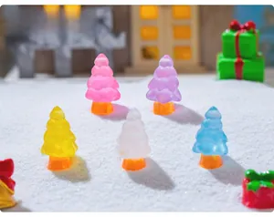 Close-up of colorful resin miniature Christmas trees on snow for DIY festive decor