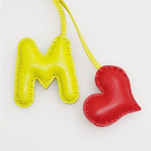Macro detail of handmade PU leather bag charm showing stitching on M-letter and heart
