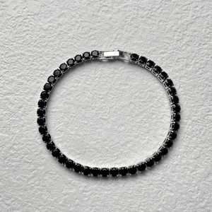 Close-up of hip hop tennis bracelet with black round-cut stones and secure clasp