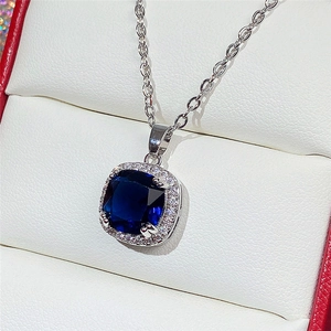 Close-up of a silver necklace with a square blue gemstone pendant in a white jewelry box