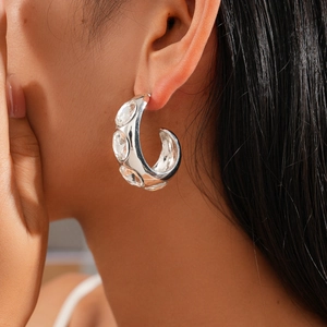Silver geometric C-shape earring with rhinestones on model ear for luxury fashion look