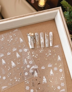 Détail de stickers à ongles de Noël avec flocons dorés et élans sur fond en bois