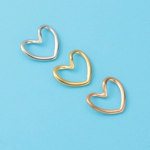 Three-color hollow heart pendants in silver, gold, and rose gold on a blue surface