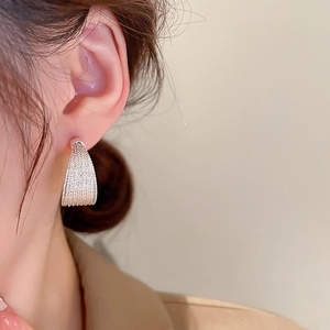 Detailed close-up of textured silver geometric hoop earrings worn by a model
