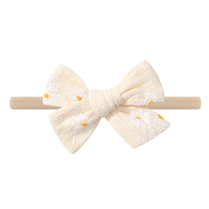 Detail of baby headband with daisy pattern and a soft fabric bow in light beige