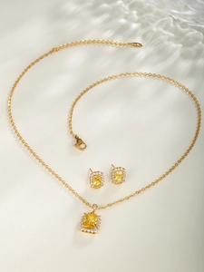 Detail of elegant gold-tone jewelry set with rectangular yellow gems and cubic zirconia