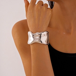 Close-up of a silver wavy wide cuff bracelet with a polished finish on a female wrist