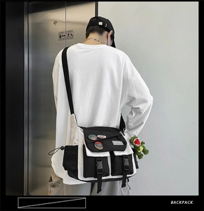 Detail view of canvas messenger bag with green dinosaur plush and black white contrast