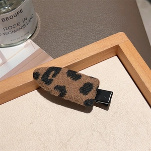 Detailed view of leopard print fabric hair clip on a wooden tray with elegant background