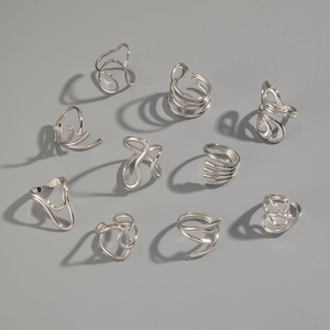 Flat lay of multiple abstract fluid geometric silver rings in modern minimalist style