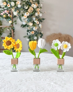 Detailed view of handmade crochet sunflower and tulip in glass jars with wooden lids