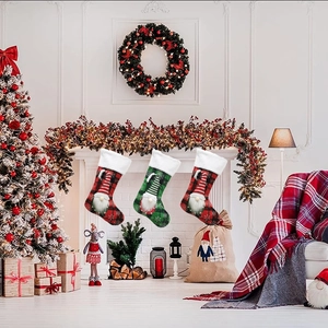 Three 3D gnome Christmas stockings hanging on fireplace with red and green plaid patterns