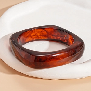 Detail of a thick rectangular amber resin bangle with a vintage tortoiseshell texture