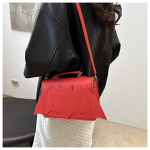 Detail of red bat wing crossbody bag with adjustable strap and textured PU leather