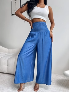 Detalle de pantalones azules de pernera ancha con cintura alta fruncida satinada