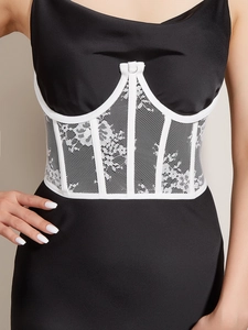 Detailed view of black corset vest with white lace embroidery and fishbone structure