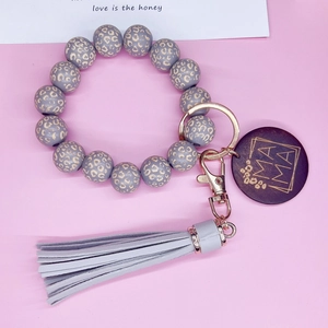 Détail du porte-clés en silicone léopard avec étiquette MAMA en bois et gland gris