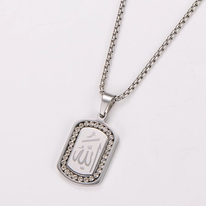 Vue macro du pendentif rectangulaire argenté orné de strass et d'une gravure arabe