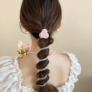 Détail d'un chouchou rose en forme de fleur et d'un cordon spirale en argent sur queue