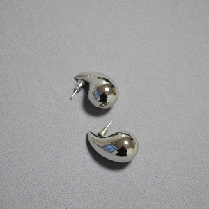 Macro shot of minimalist silver hollow teardrop earrings on a textured grey background