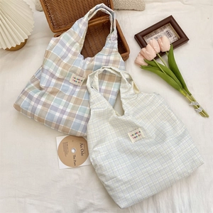 Detail of checkered fabric tote bag with brand label on textured rustic background