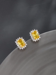 Macro shot of rectangular yellow gem earrings with halo diamond set in silver