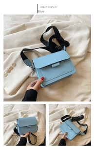 Detail of light blue square crossbody bag with wide black strap on beige blazer