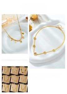 Detail of layered gold necklaces with butterfly pendant and tree of life charms on white plate