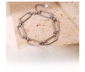 Detailed view of silver titanium steel chain bracelet on a beige textured stone base