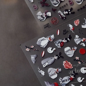 Macro shot of 3D embossed Japanese nail stickers with fox and crane art on dark grey base